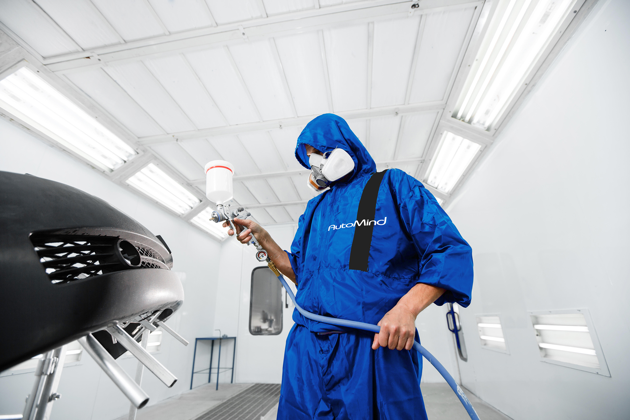 H5J7X8 worker painting a car black blank parts in special garage, wearing costume and protective gear